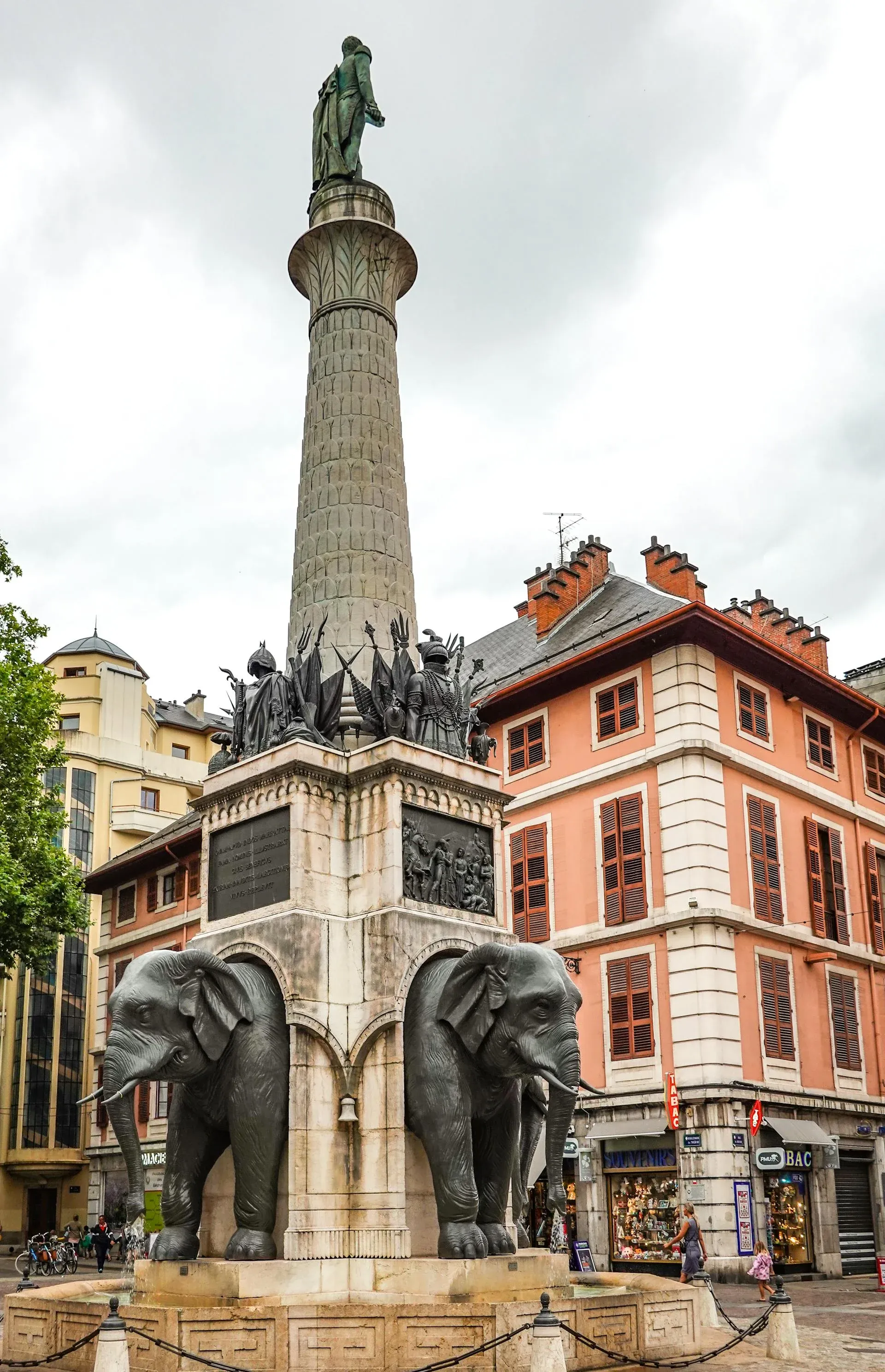 Fonte dos Elefantes em Chambéry, França, com um monumento alto e prédios históricos ao redor