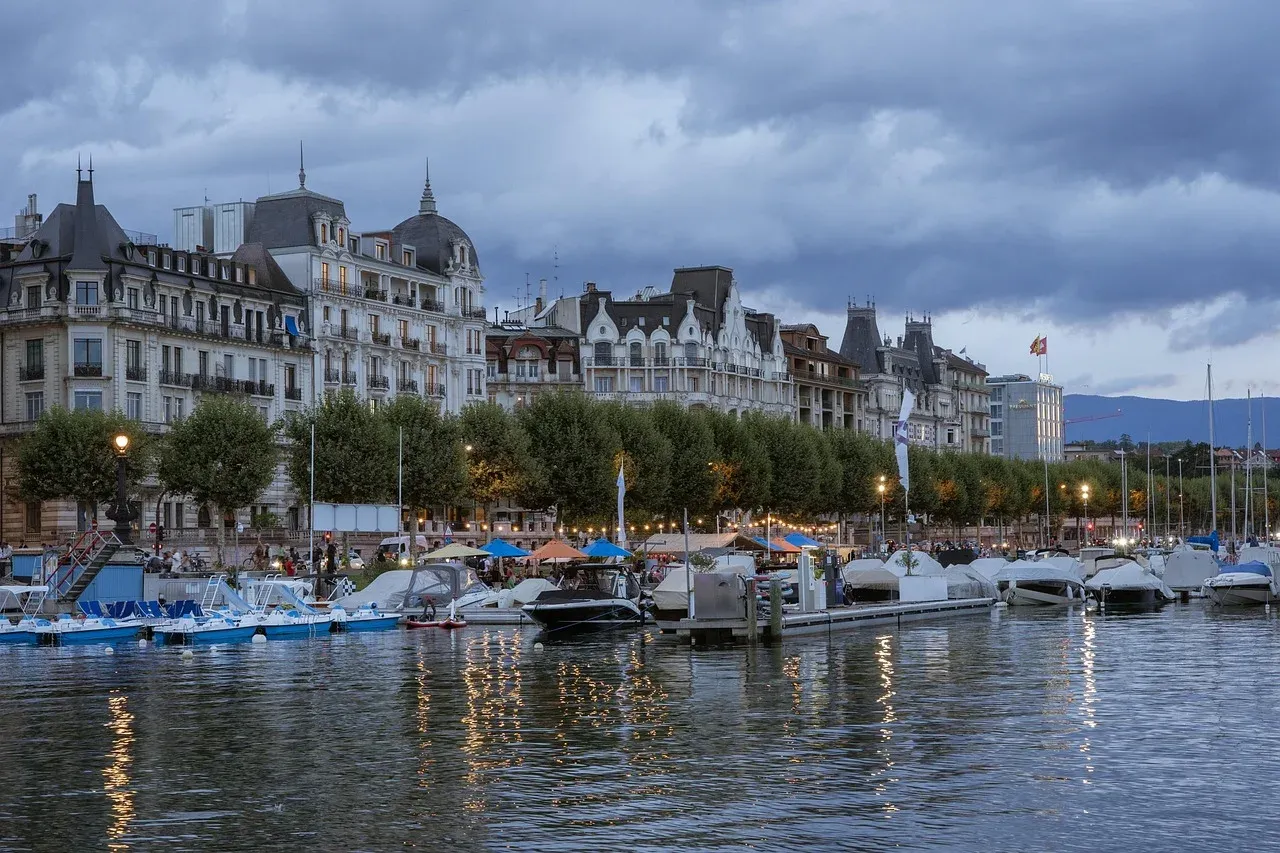 Quai Wilson à Genève avec bateaux et bâtiments historiques sous un ciel nuageux
