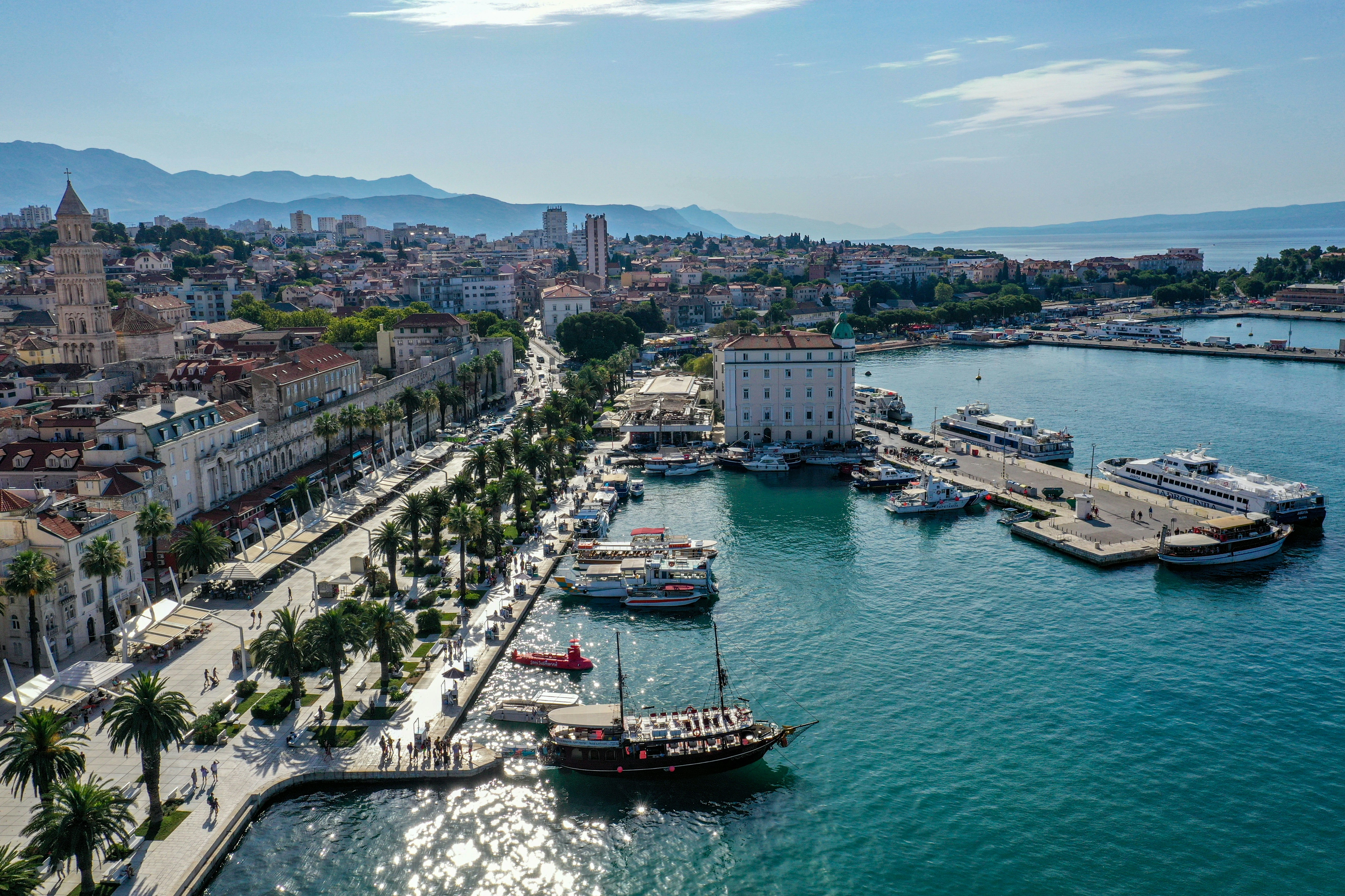 Elevated view of Split, Croatia, showcasing its vibrant Riva promenade lined with palm trees, the historic city centre and bustling port